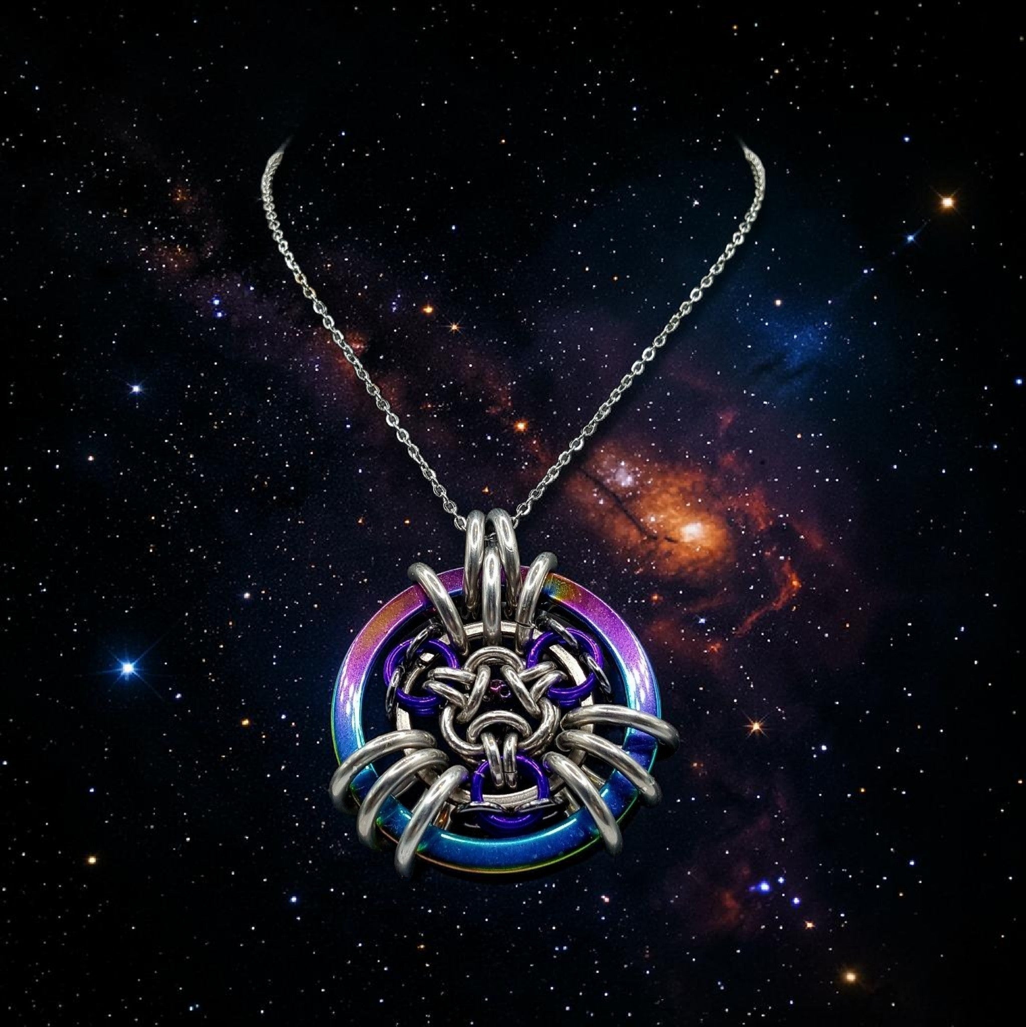 Sanctuary Studio artisan chainmaille pendant necklace with iridescent rainbow and silver rings against a cosmic sky.